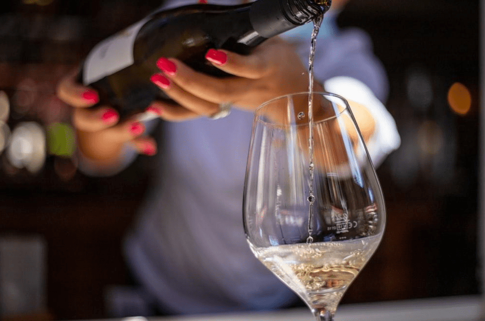 A person pouring white wine into a glass