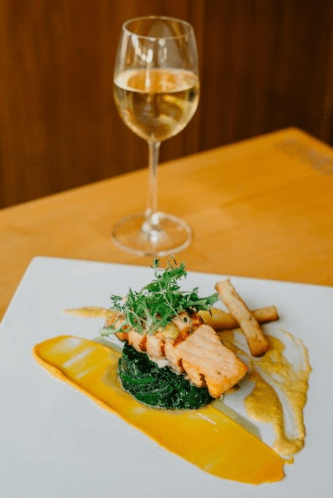 A plate of salmon next to a glass of wine